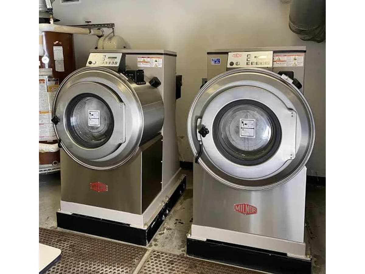 Pair of commercial Milnor washers in a laundry equipment room