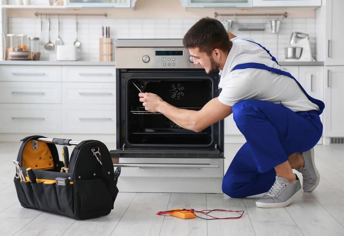 Technician repairing an oven in a kitchen